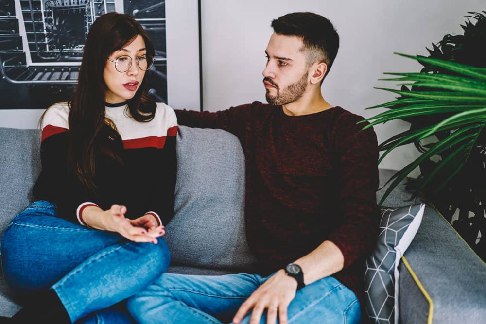 A man and woman have a serious talk on a couch.