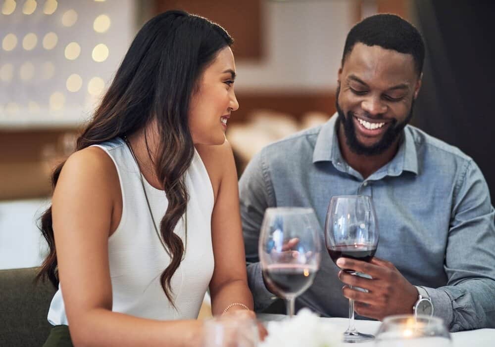 A couple on a date both have a glass of wine.