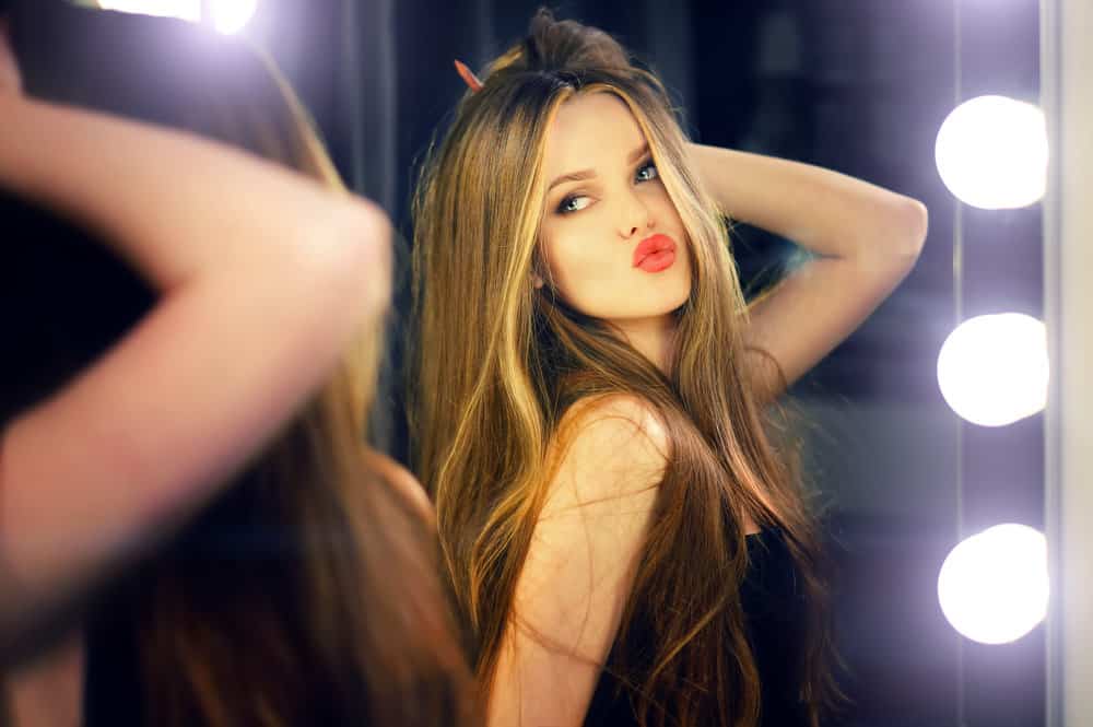 A woman purses her lips and poses in front of a mirror.