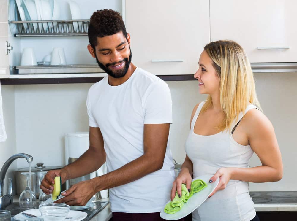 Newlyweds make the washing up together and smiling