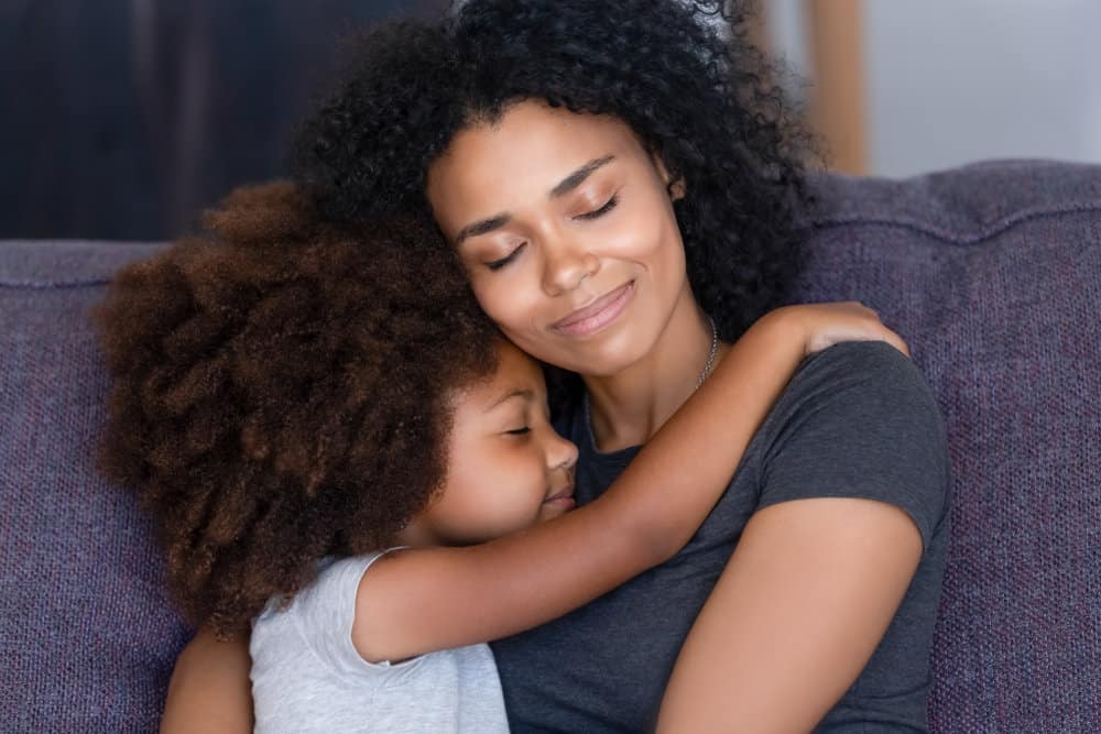 Eine glückliche Mutter und Tochter zusammenkuscheln