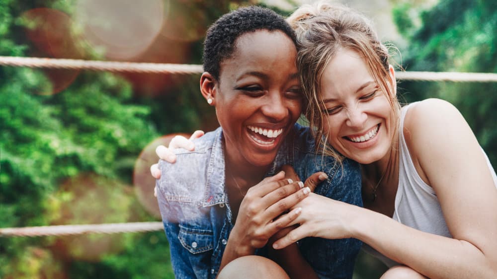 Two women cuddle together and laugh