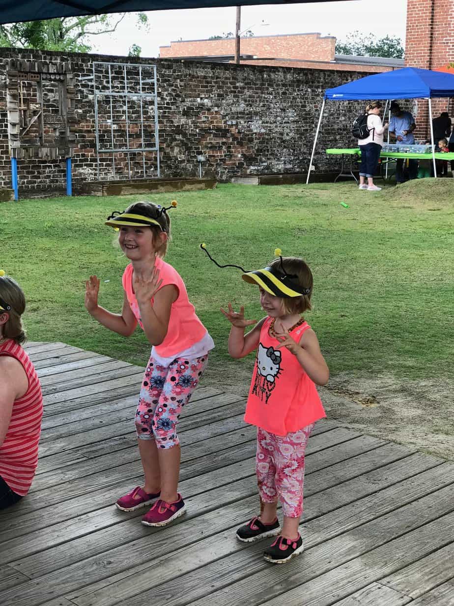 Two little kids are outdoors dancing while having fun.