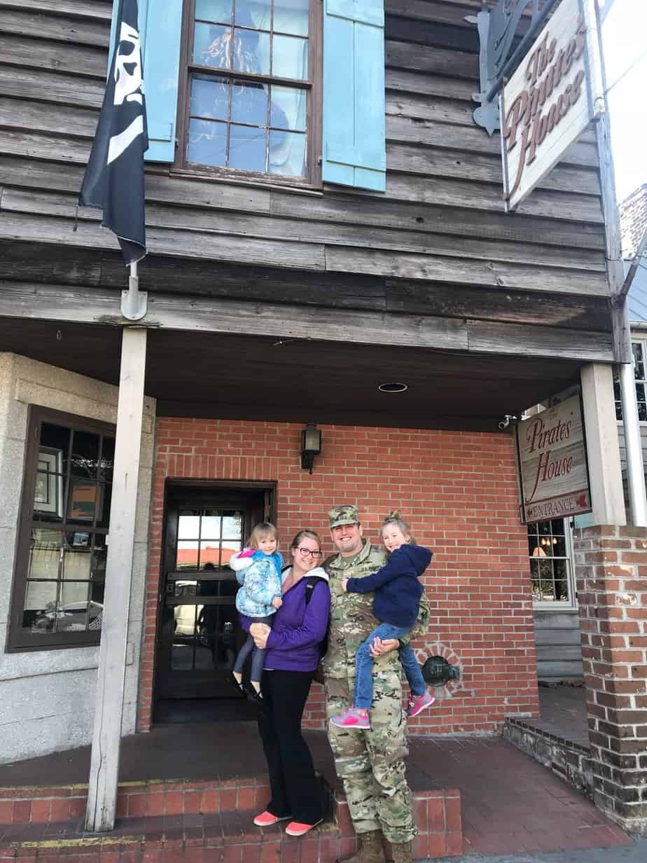 A family stand sin front of a brick building smiling.