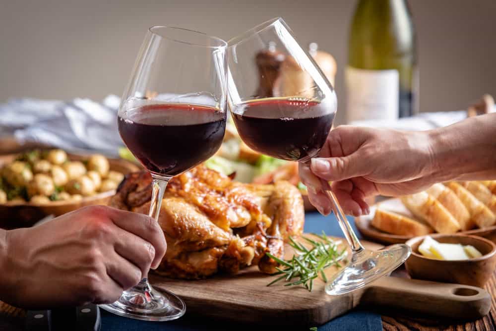 Some wine glasses clink together at a lovely Thanksgiving dinner