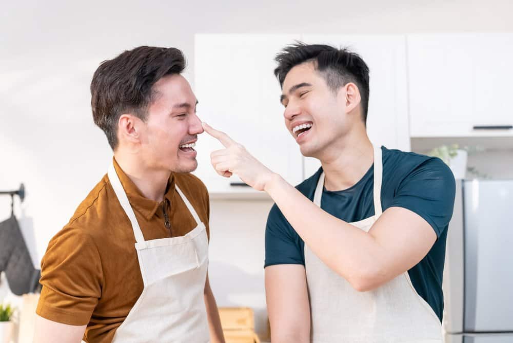 A couple playfully bakes together in a kitchen on a cute Thanksgiving date