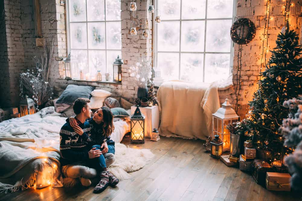 A couple embrace on the floor while sharing romantic christmas texts for him