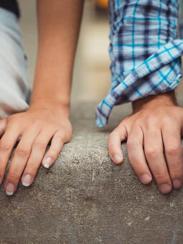 A close up of two hands on a cement wall of a couple who are dealing with bad relationship advice