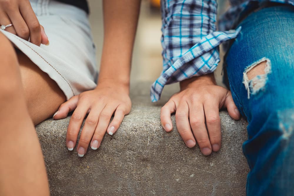 A close up of two hands on a cement wall.