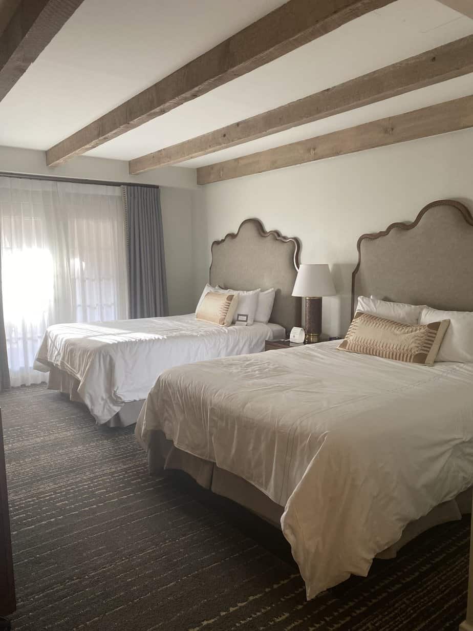 Two beds in La Mansion del Rio Bravo hotel room in San Antonio with exposed beams and natural light