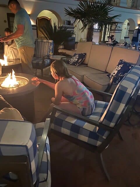 A child warms herself by a firepit in the courtyard of one of the most popular hotels in San Antonio