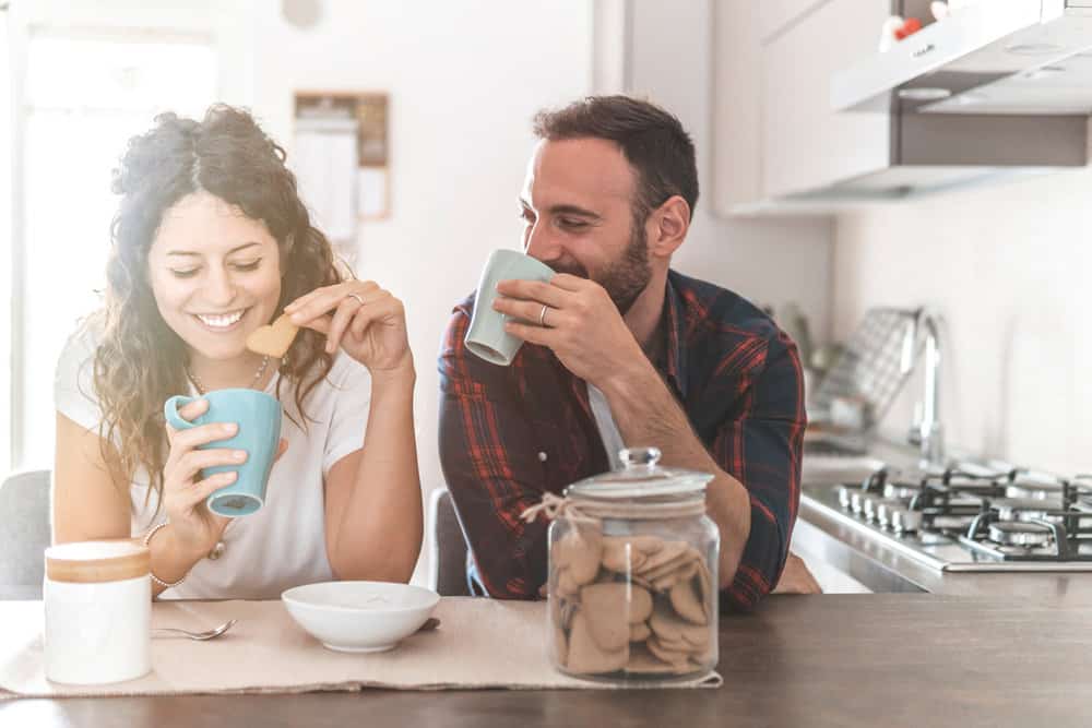 A couple sits and has coffee together while playing a relationship version of Never Have I Ever