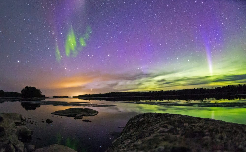 A purple and green sky with aurora borealis present is seen in the USA