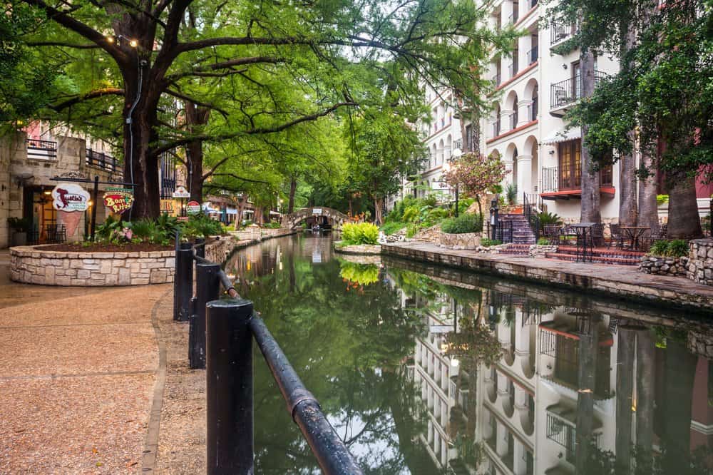 The San Antonio river walk with stone walkways and historic hotels lining the river